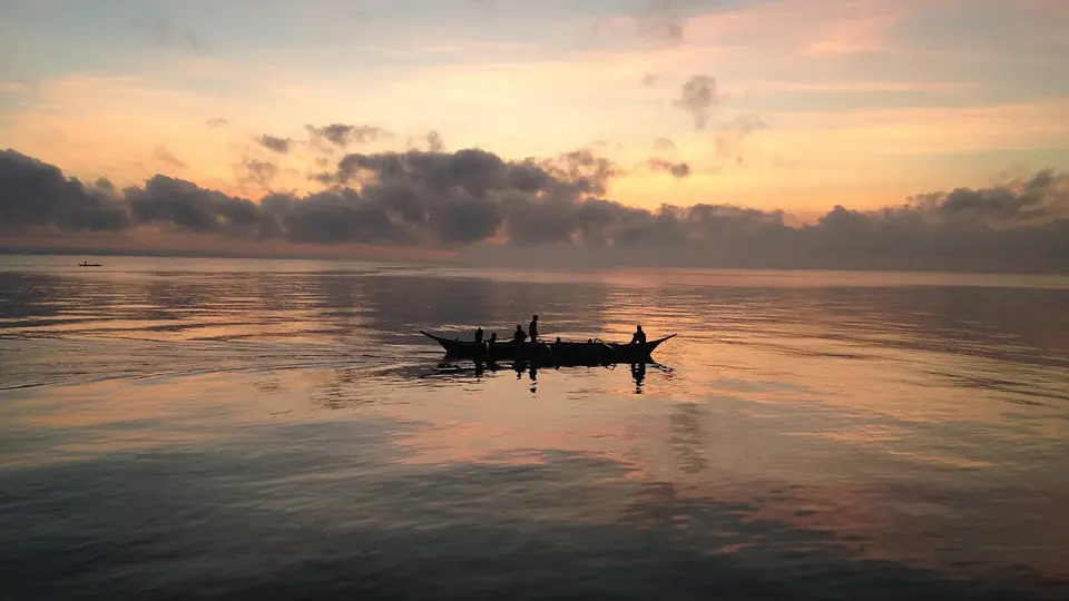 Kleines Fischerboot auf spiegelglattem Wasser in der Abenddämmerung